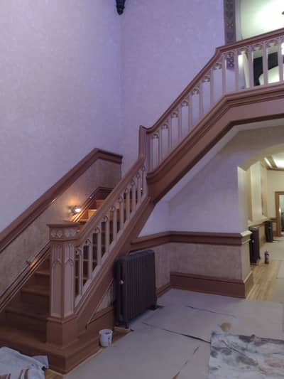 Interior staircase with lavender-painted walls, white trim, and dark wooden railings.