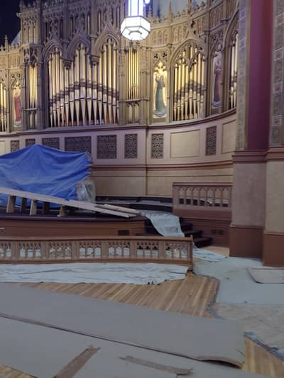 Interior of a religious building featuring a pipe organ with protective blue coverings.