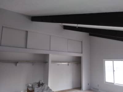 Interior ceiling area with black exposed beams and built-in shelving units.