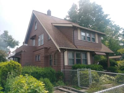 Brown and tan siding house with pitched roof and side yard view.
