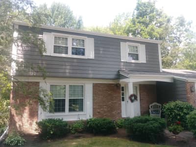 Gray siding house with white accents and mixed material details.