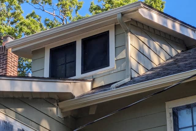 A freshly painted dormer and eave with white trim against a blue sky.
