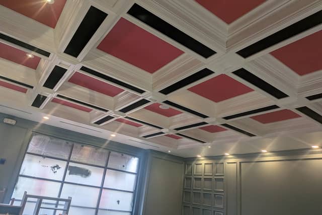 A coffered ceiling with white beams, black inlays and deep red panels.